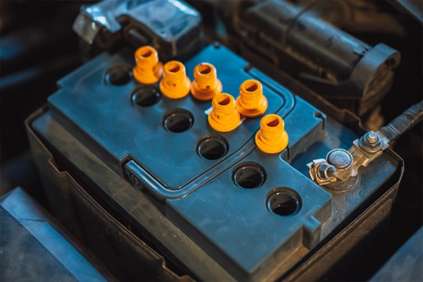 Close-up image of a car battery in a car with plugs removed. 